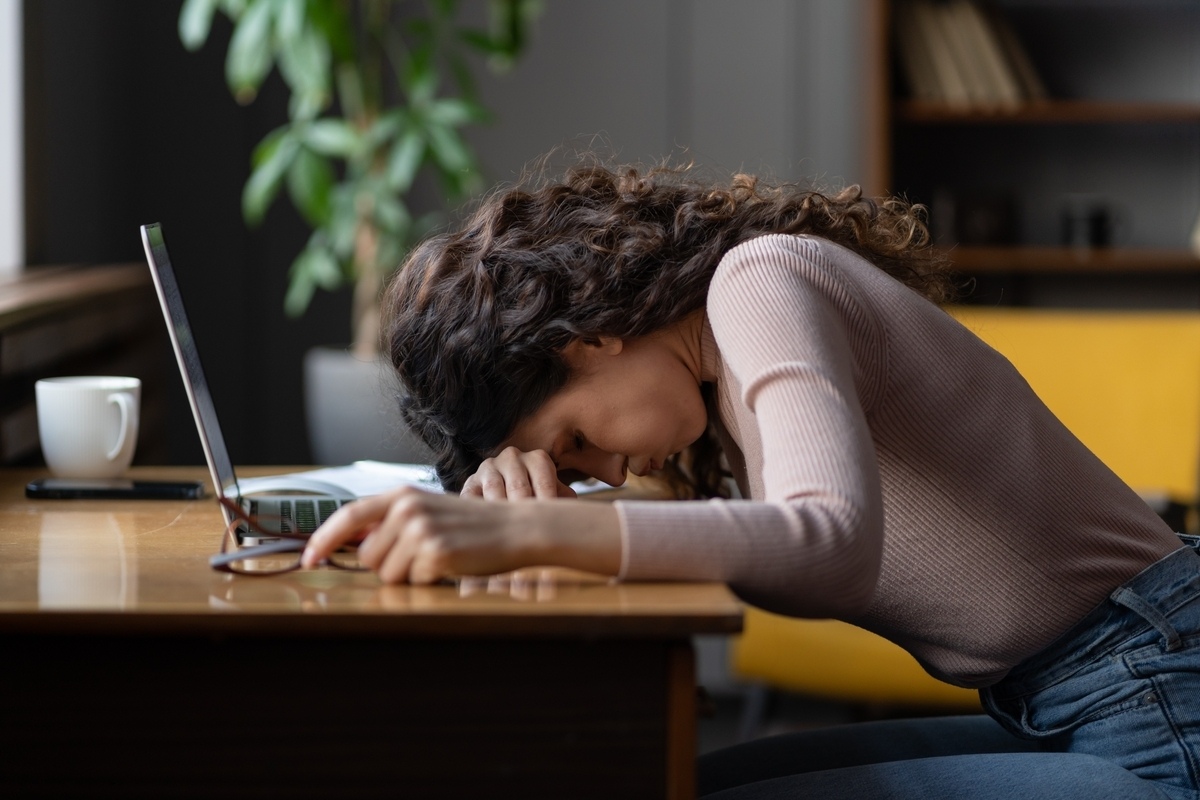 Exhausted adult slumped at a desk representing the connection between ADHD and burnout