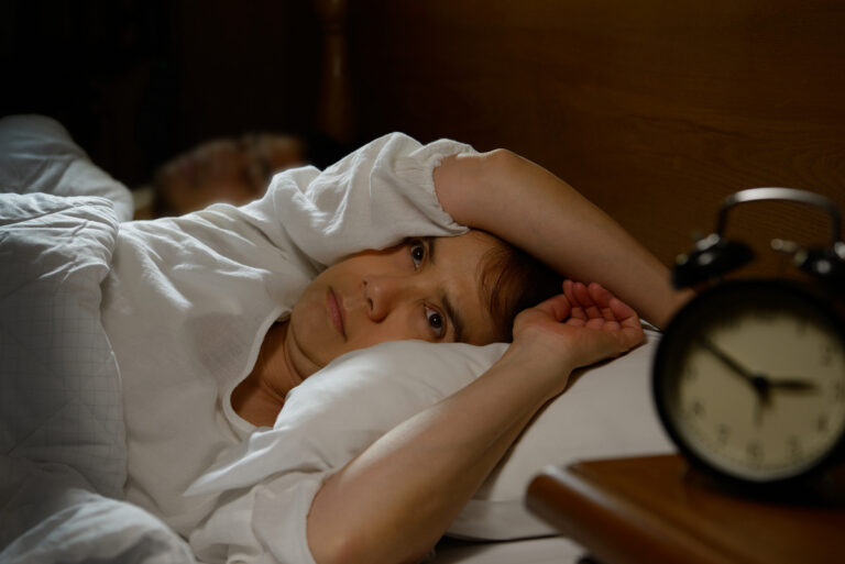 Adult lying awake in bed at night representing the connection between ADHD and sleep difficulties