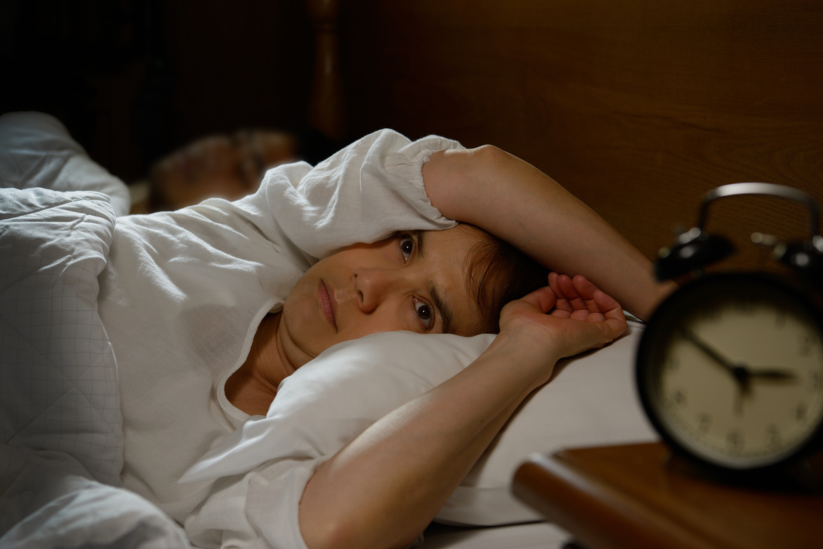 Adult lying awake in bed at night representing the connection between ADHD and sleep difficulties
