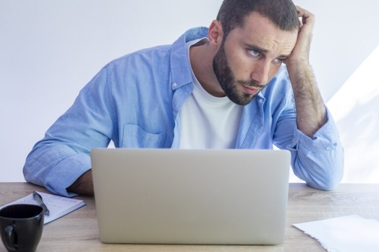 Adult man at a desk struggling to start work representing the experience of executive dysfunction in ADHD