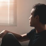 Adult sitting quietly and reflectively representing the connection between unresolved trauma and depression