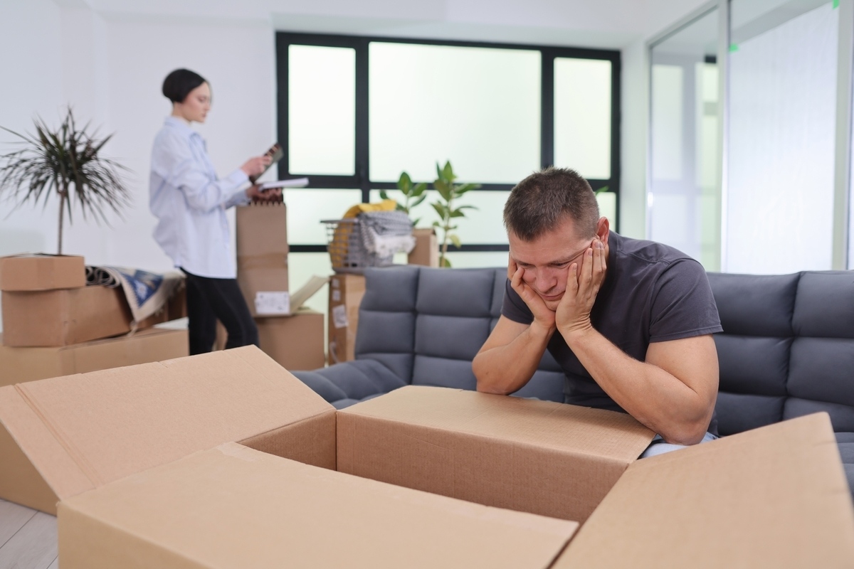 Adult sitting quietly amid moving boxes representing the connection between life transitions and depression